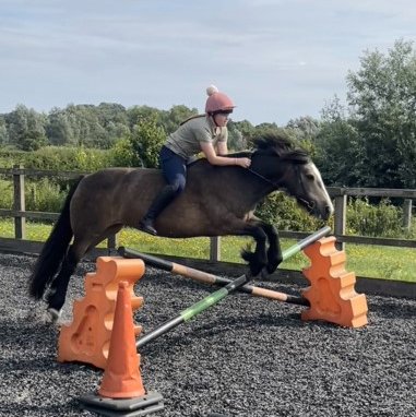 child riding over a jump on a pony with no saddle