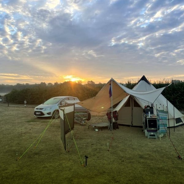 misty morning with sun rising above a tent