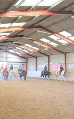 horse riding group in indoor arena