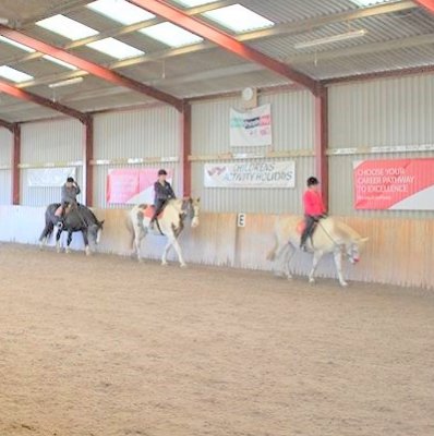 horse riding group in indoor arena