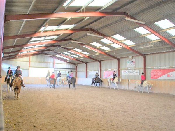 horse riding group in indoor arena